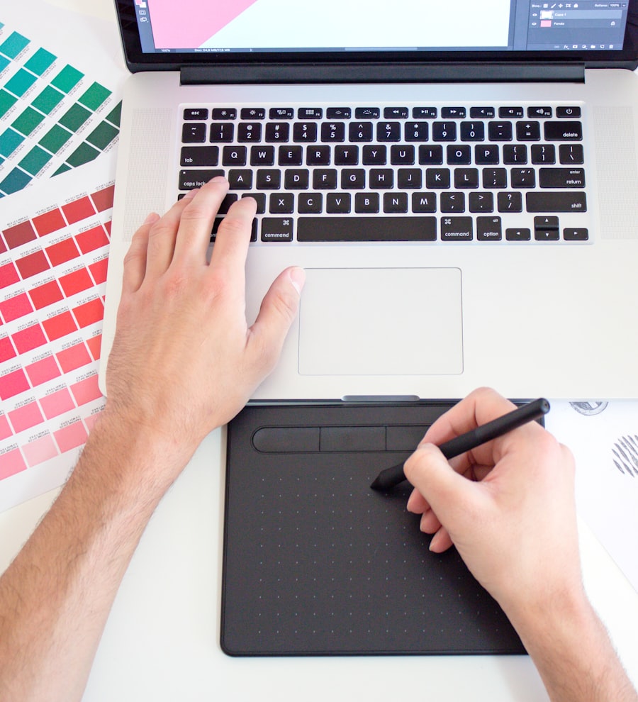 Designer working on a laptop surrounded by colour swatches and drawing tools